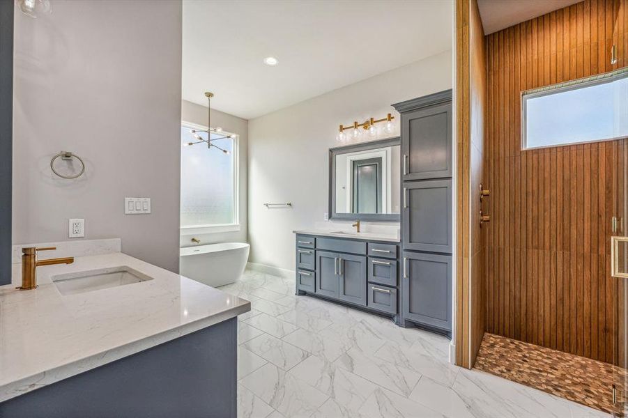 Bathroom with dual vanity, an inviting chandelier, tile patterned flooring, and a bath