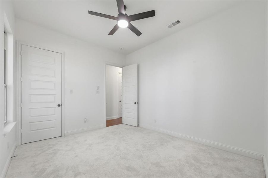 Unfurnished bedroom with light carpet and a ceiling fan
