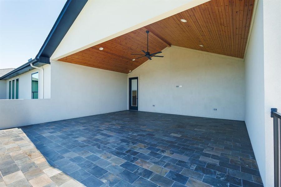 Spacious covered patio featuring slate tile flooring, a wood-finish vaulted ceiling with recessed lighting, and a ceiling fan