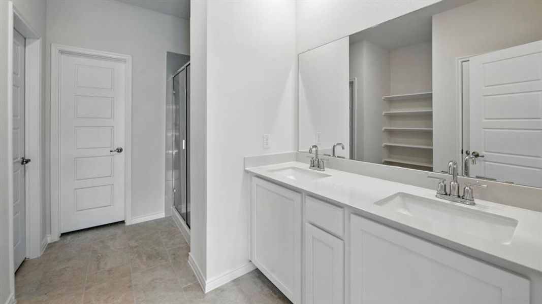 Full bath featuring a stall shower, double vanity, and a walk in closet Full bath featuring a stall shower, double vanity, and a walk in closet