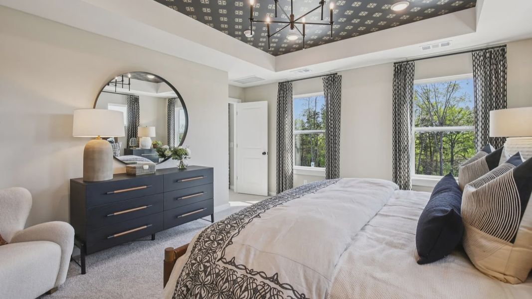 Bedroom with tray ceiling and natural light from windows