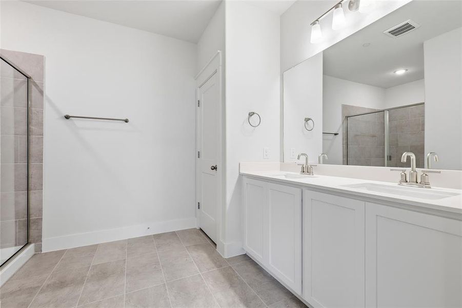 The bathroom features a double vanity with white cabinetry, a large mirror, and a glass-enclosed shower with tiled walls