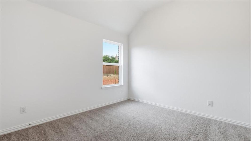 Room featuring a vaulted ceiling, neutral wall paint, and gray carpet flooring Room featuring a vaulted ceiling, neutral wall paint, and gray carpet flooring