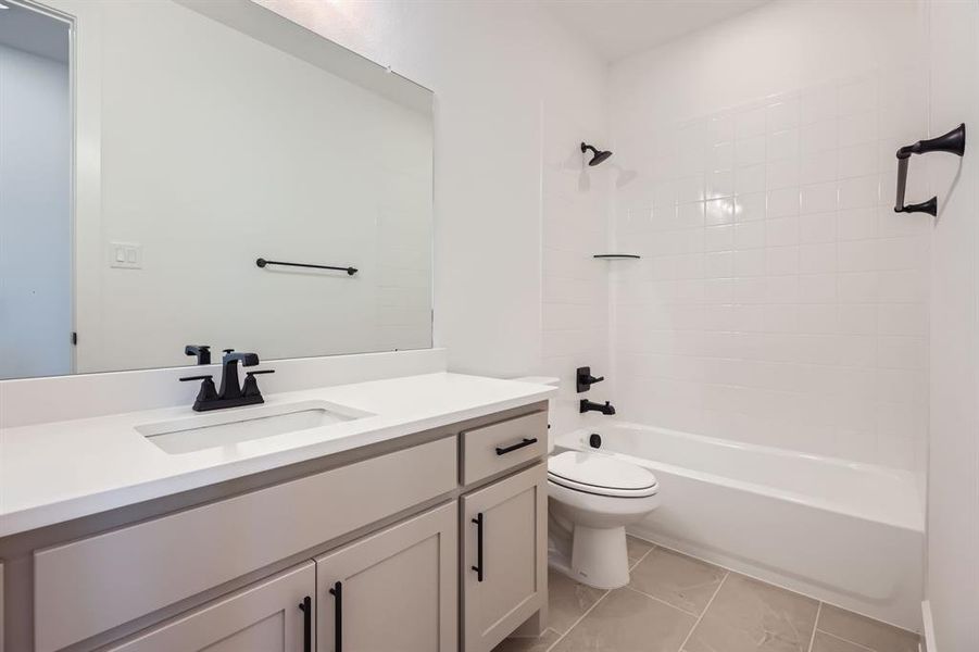 Full bathroom with vanity, toilet, shower / washtub combination, and marble look tile flooring Full bathroom with vanity, toilet, shower / washtub combination, and marble look tile flooring