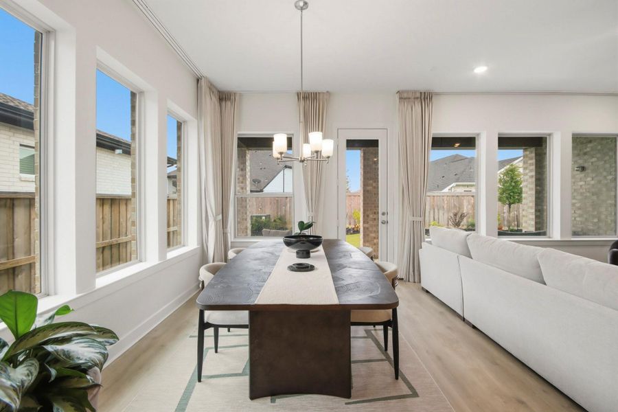 Light-filled dining area showcasing expansive windows, a sophisticated chandelier, and direct access to the backyard, providing an ideal setting for meals and gatherings.