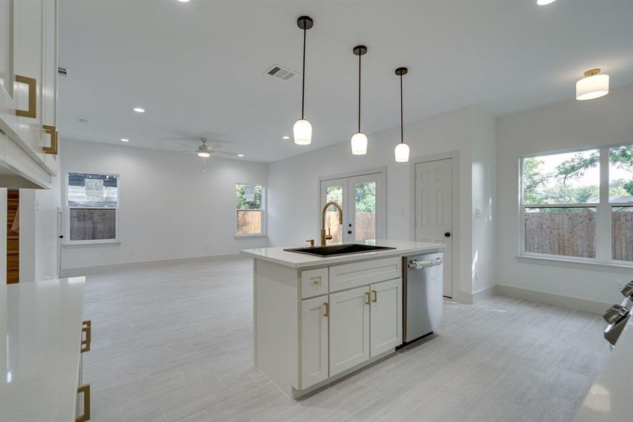 Kitchen featuring sink, an island with sink, dishwasher, ceiling fan, and white cabinets