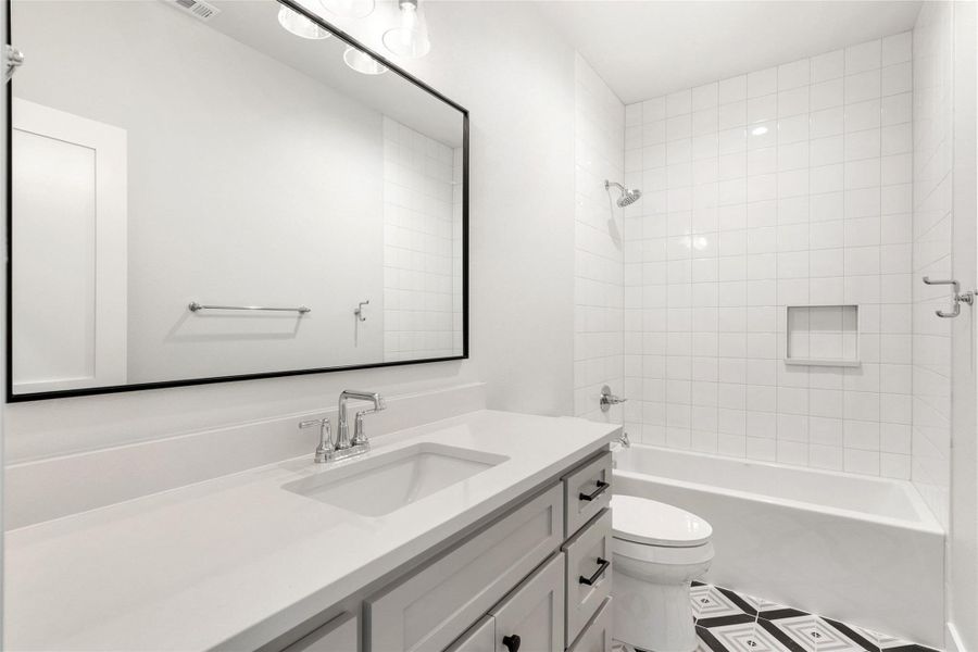 A well-appointed bathroom features a single vanity, sleek fixtures, and a clean, tiled bath area.