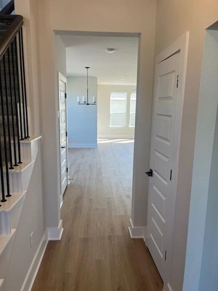 Hallway with light wood-style flooring and a chandelier Hallway with light wood-style flooring and a chandelier