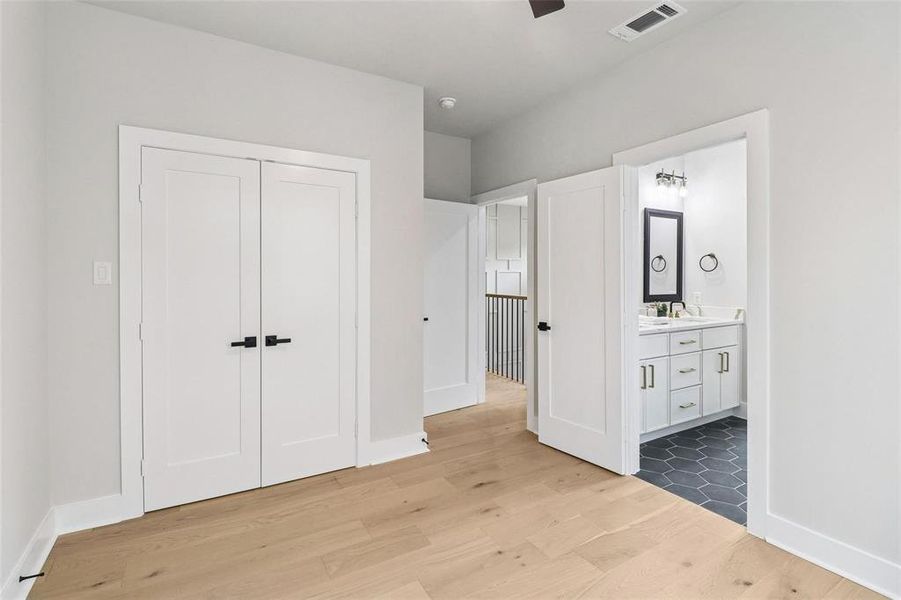 This interior space features light-toned hardwood flooring, white walls, and white doors with black hardware