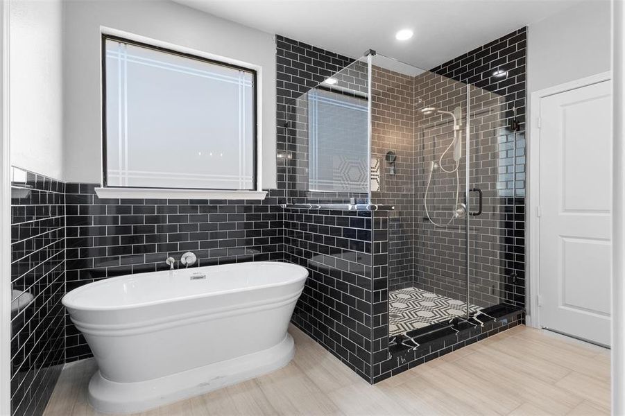 Bathroom with tile walls, a freestanding tub, and a stall shower