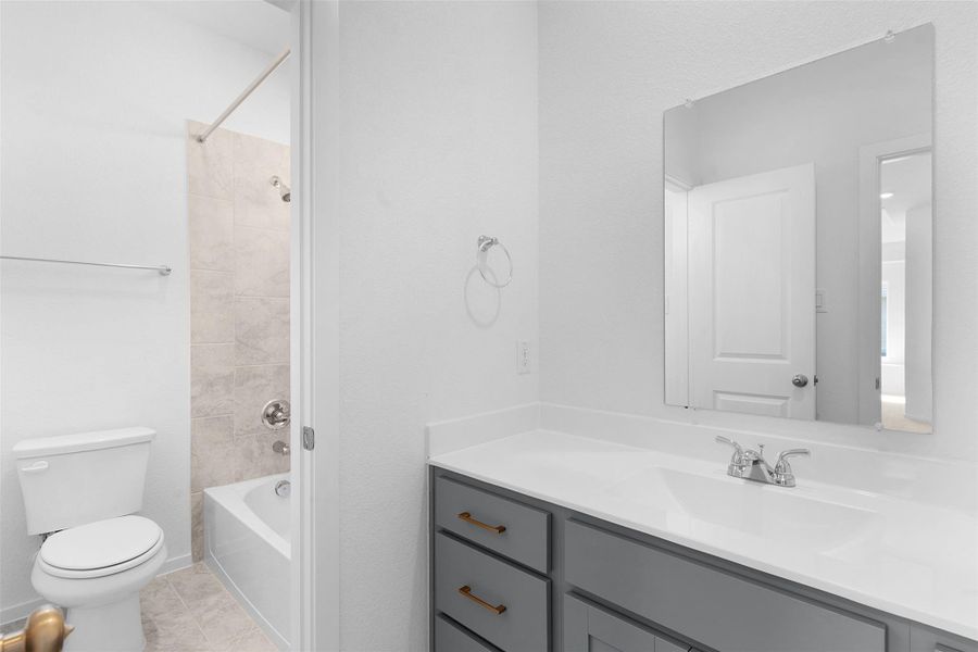 Full bath featuring vanity, bathing tub / shower combination, and light tile patterned floors Full bath featuring vanity, bathing tub / shower combination, and light tile patterned floors