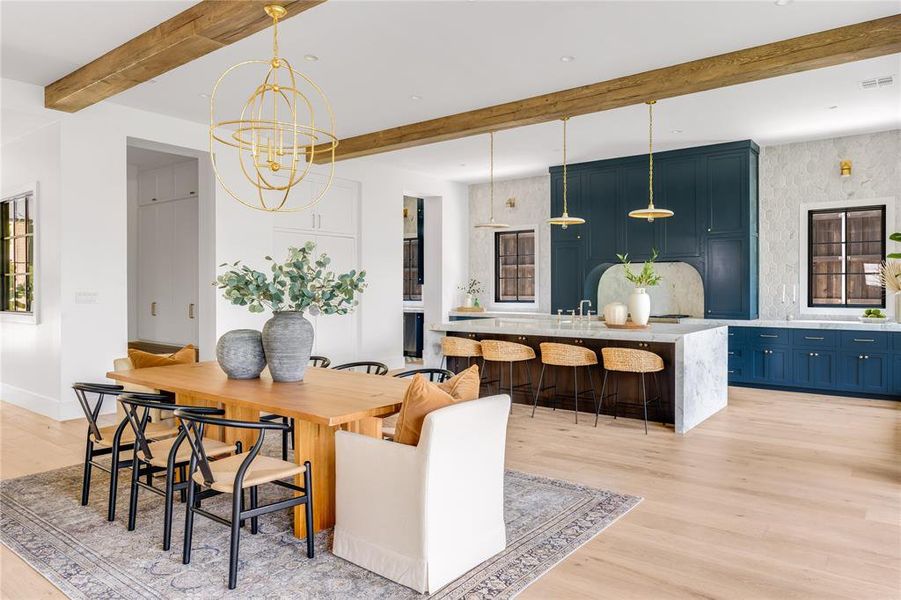 Dining area featuring light wood-type flooring, beam ceiling, and a chandelier