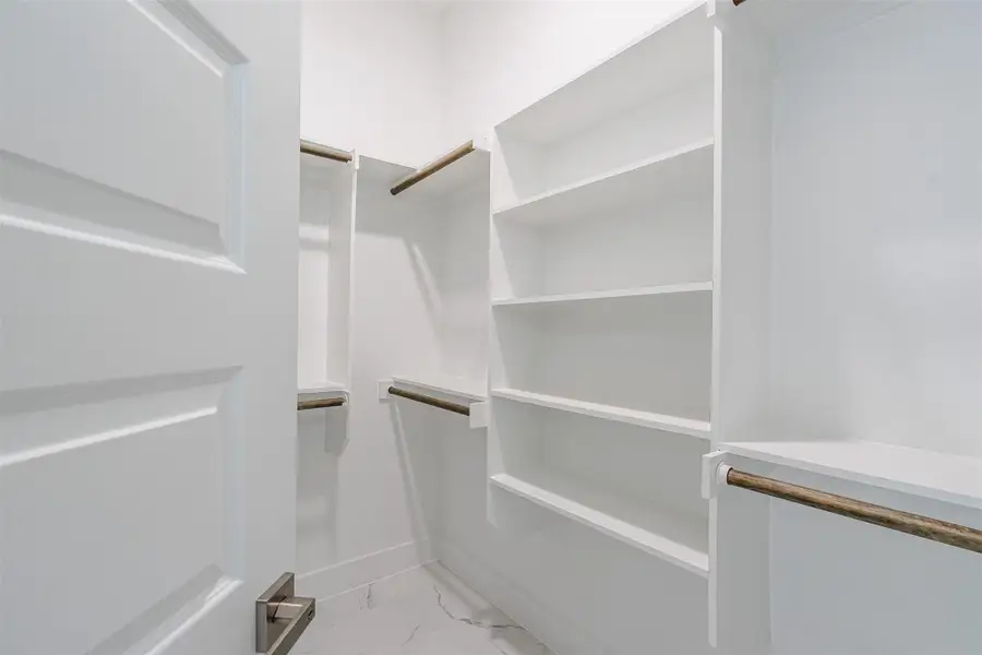 Ample shelving and hanging space offer organized storage in this pristine walk-in closet. Ample shelving and hanging space offer organized storage in this pristine walk-in closet.