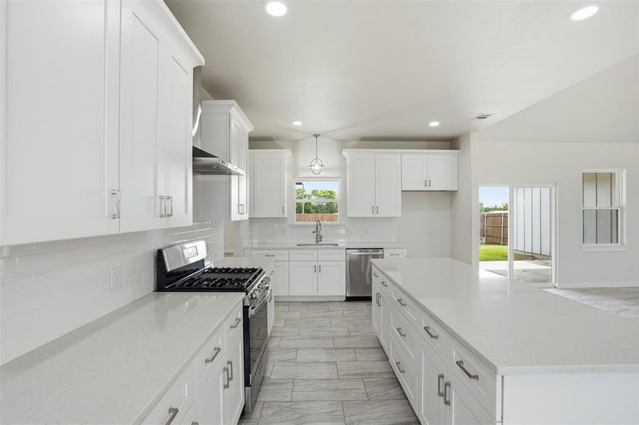 Modern kitchen featuring white shaker cabinetry, light-toned countertops, and stainless steel appliances
