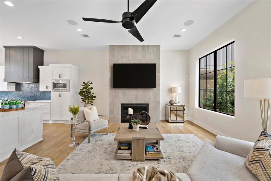 Step inside to a warm and welcoming living room filled with natural light. The tile clad fireplace makes an impactful statement as it extends to the twelve foot ceiling. TV in the photo is virtually rendered.