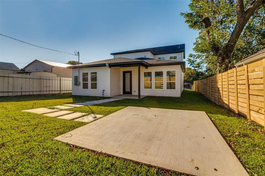 Rear view of house with a patio, a fenced backyard, and roof with shingles
