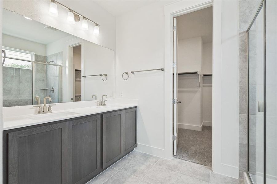 Bathroom with a shower with door, vanity, and tile patterned floors