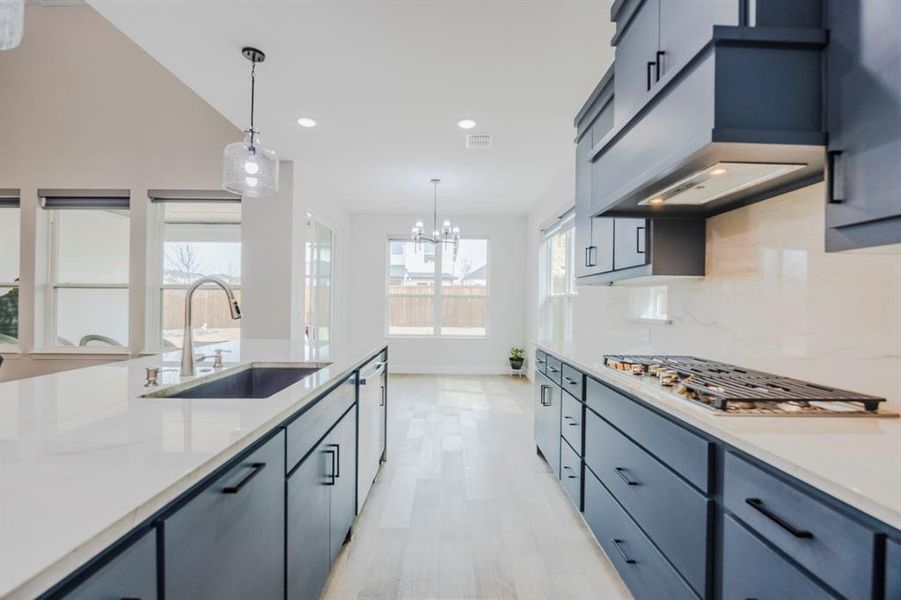 Kitchen featuring stainless steel gas cooktop, a sink, decorative light fixtures, backsplash, and a chandelier