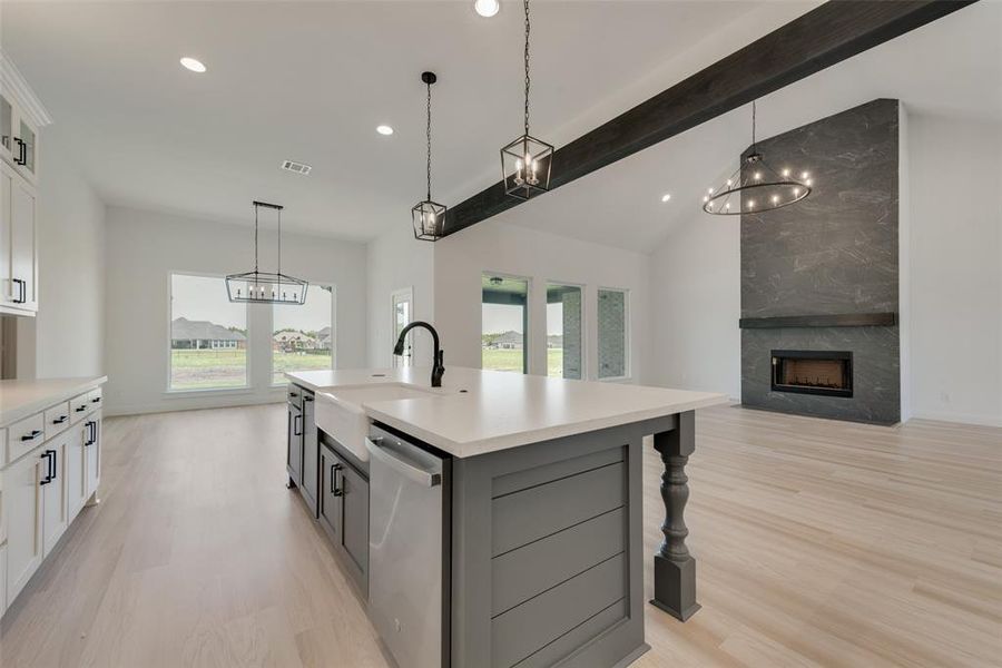 Kitchen with stainless steel dishwasher, a kitchen island with sink, light hardwood / wood-style flooring, and white cabinets