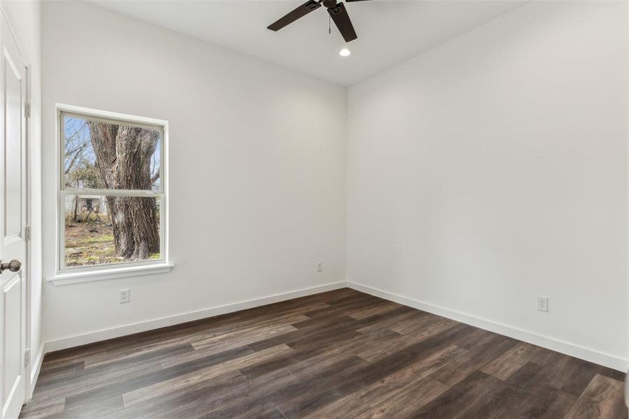 Spare room with dark wood-type flooring and ceiling fan