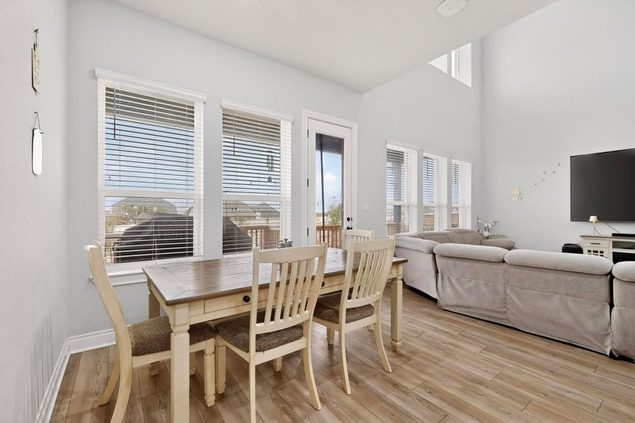 Dining area with light wood-style floors and a high ceiling