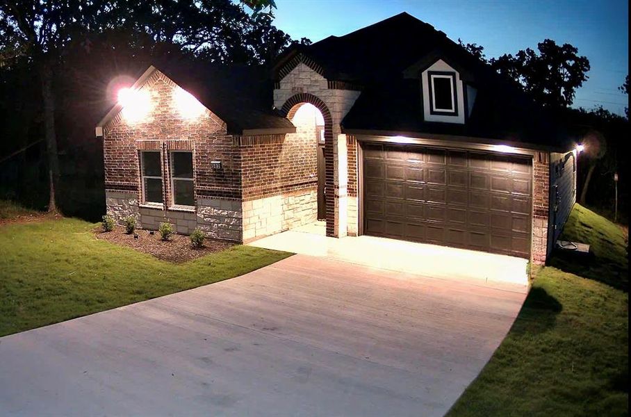 Brick and stone exterior featuring an arched entryway, gabled roofline, and dormer window