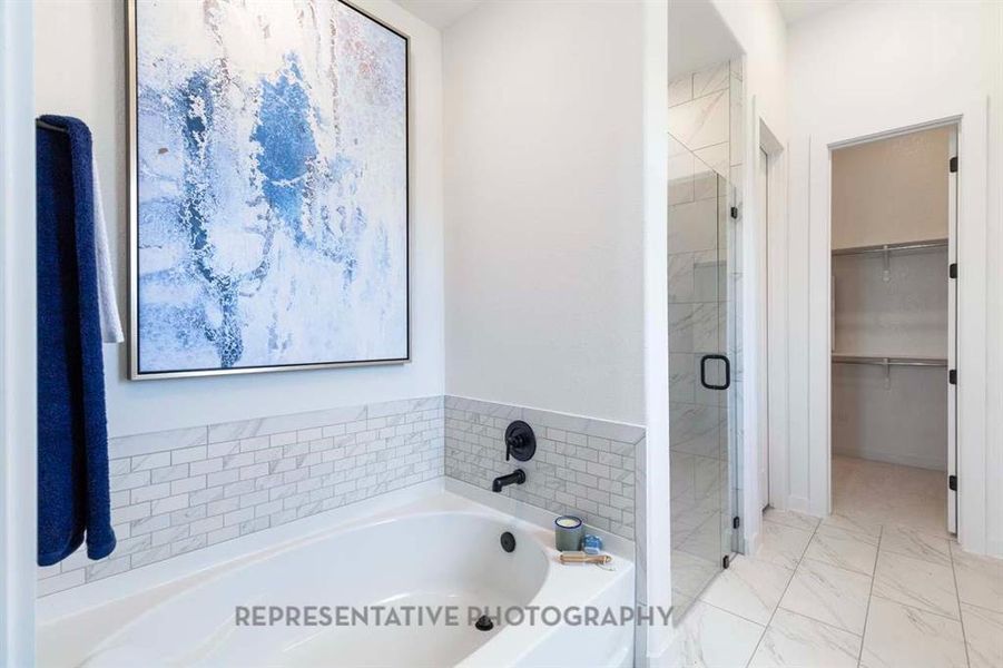 Full bath with a stall shower, a bath, light marble finish floors, and a walk in closet Full bath with a stall shower, a bath, light marble finish floors, and a walk in closet