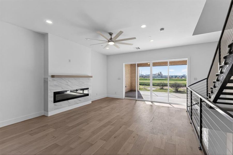 Unfurnished living room featuring a premium fireplace, light wood-type flooring, a ceiling fan, and recessed lighting