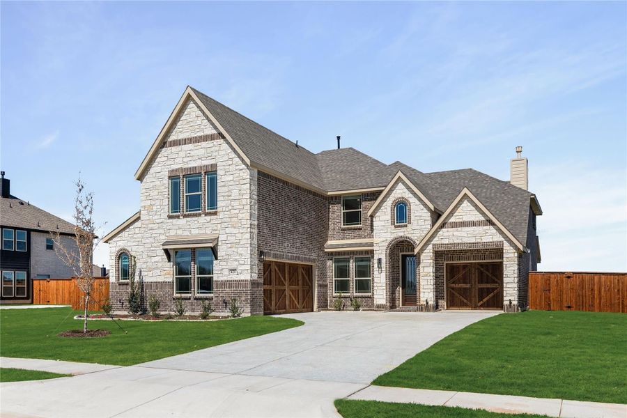 Two-story home with stone and brick exterior, three-car garage, and concrete driveway Two-story home with stone and brick exterior, three-car garage, and concrete driveway