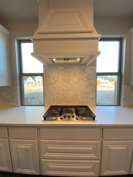 GAS 5 burner cooktop with custon cabinet vent hood to the outside, pot & pan drawers, and windows on each side for natural light