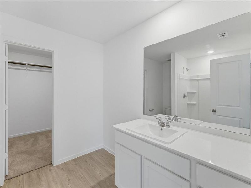 Bathroom vanity featuring a single basin, chrome faucet, and expansive countertop