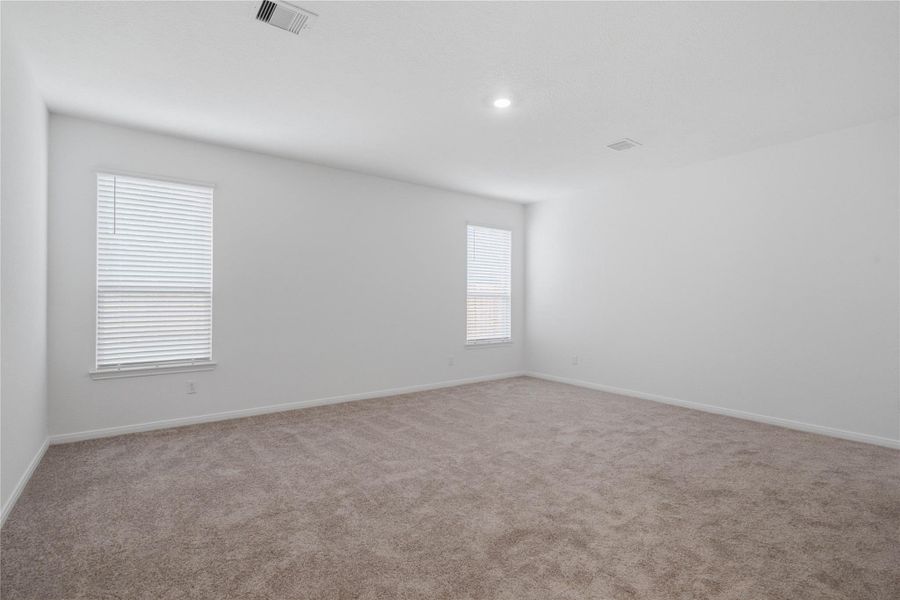 Unwind after a long day in this stunning primary suite! This spacious retreat features plush carpeting, neutral-toned walls, soaring ceilings, recessed lighting, and large windows with privacy blinds for comfort and tranquility.