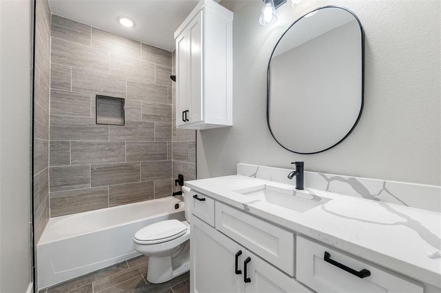 Full bathroom with vanity, tiled shower / bath combo, and toilet