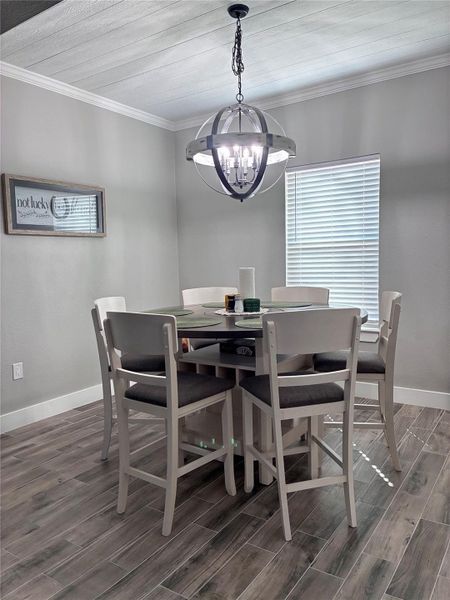 Dining area featuring crown molding, wood finish floors, and a chandelier