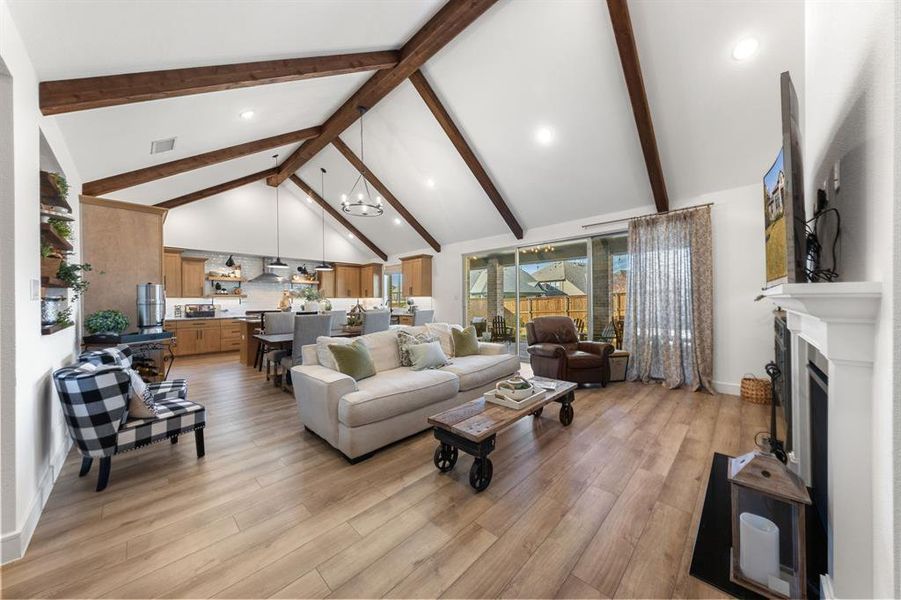 Vaulted ceiling with wood beams, triple-slider doors, and natural light throughout the open-concept living space.