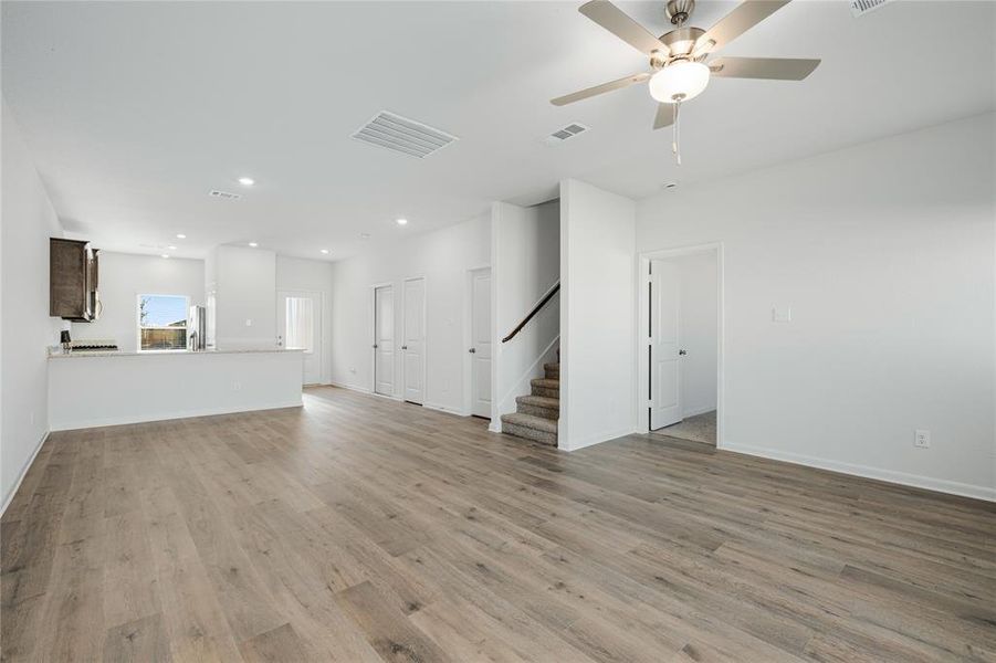 Unfurnished living room with light wood finished floors, stairway, recessed lighting, and ceiling fan