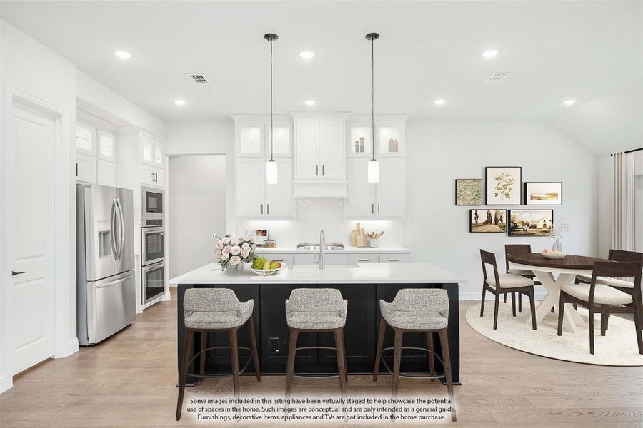 White kitchen with dark island, three bar stools, pendant lights, and stainless steel appliances, open to dining area. White kitchen with dark island, three bar stools, pendant lights, and stainless steel appliances, open to dining area.