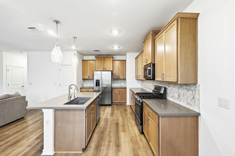 Kitchen with stainless steel appliances, tasteful backsplash, an island with sink, open floor plan, and pendant lighting