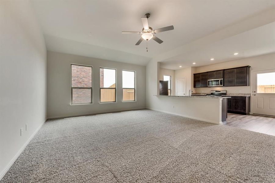 Unfurnished living room with a healthy amount of sunlight, sink, ceiling fan, and light hardwood / wood-style flooring