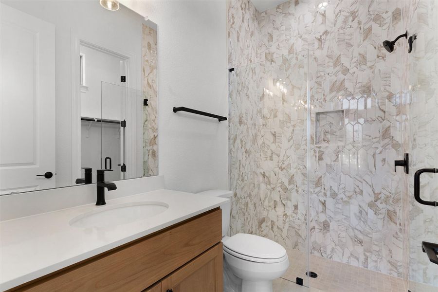 A well-appointed bathroom features a single vanity and a sleek, glass-enclosed shower.