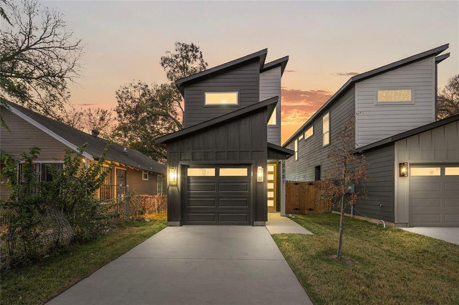 Modern home with board and batten siding, a garage, and driveway
