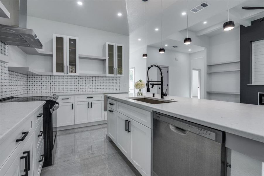 Kitchen with white cabinets, sink, stainless steel dishwasher, wall chimney exhaust hood, and decorative light fixtures