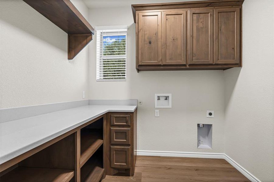 Washroom featuring light wood-style floors, washer hookup, electric dryer hookup, a textured wall, and hookup for a gas dryer