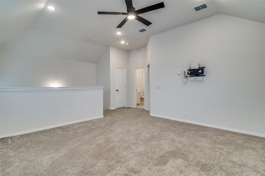 Bonus room featuring ceiling fan, lofted ceiling, and light carpet