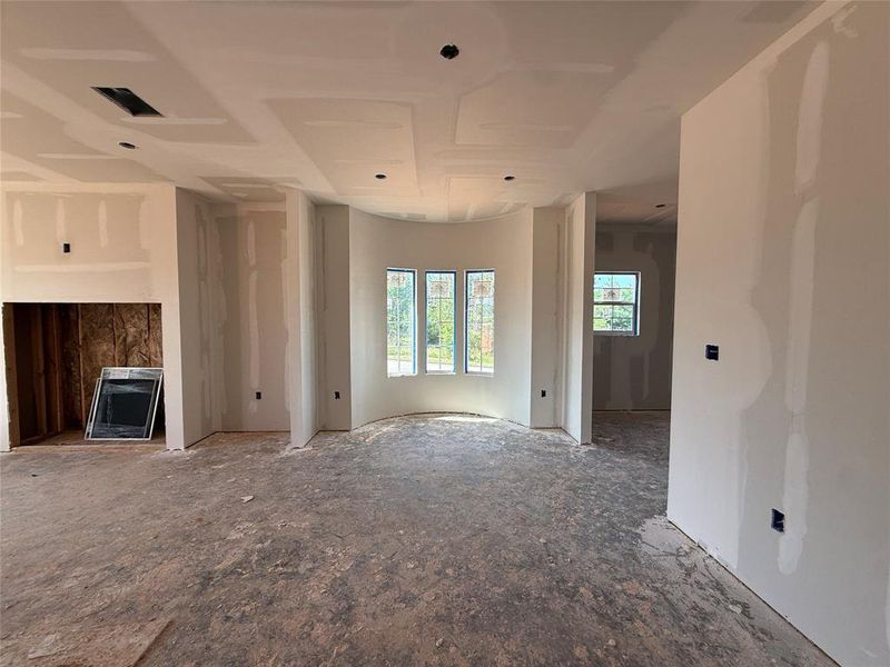 Interior space featuring drywall installation and a curved window wall with three individual windows Interior space featuring drywall installation and a curved window wall with three individual windows