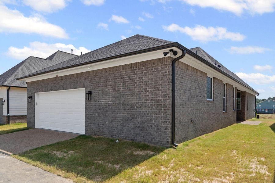 View of side of property featuring a garage, brick siding, a yard, driveway, and roof with shingles View of side of property featuring a garage, brick siding, a yard, driveway, and roof with shingles