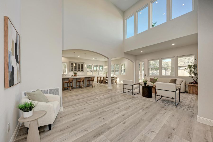 Living area with arched walkways, recessed lighting, and light wood-style floors