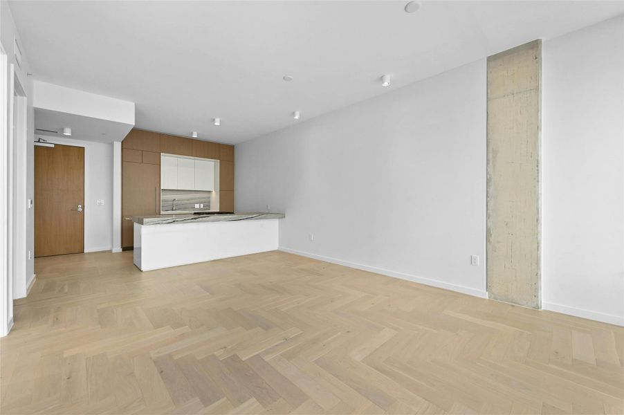 Residence 1702 showcases the A2 floorplan with open living and dining framed by herringbone oak floors and clean architectural lines. The modern kitchen features a waterfall island with stone counters, custom cabinetry, and integrated Bosch® appliances.