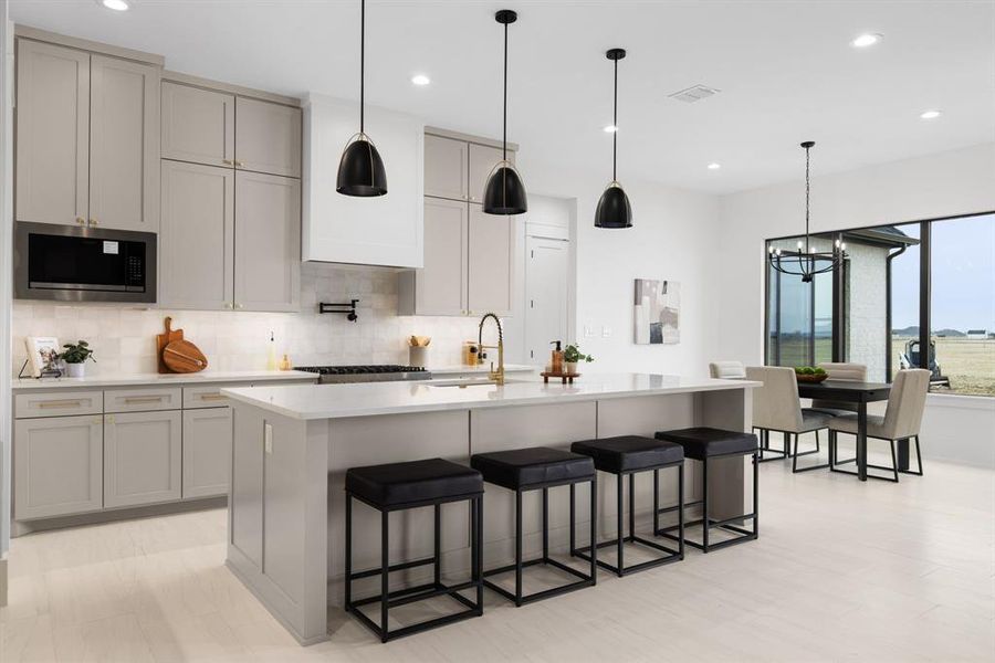 Kitchen featuring gray cabinets, tasteful backsplash, a large island, and stainless steel microwave