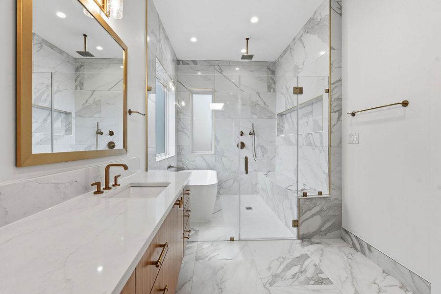 Gleaming tiles and premium gold fixtures create a luxurious and refined primary bathroom retreat.